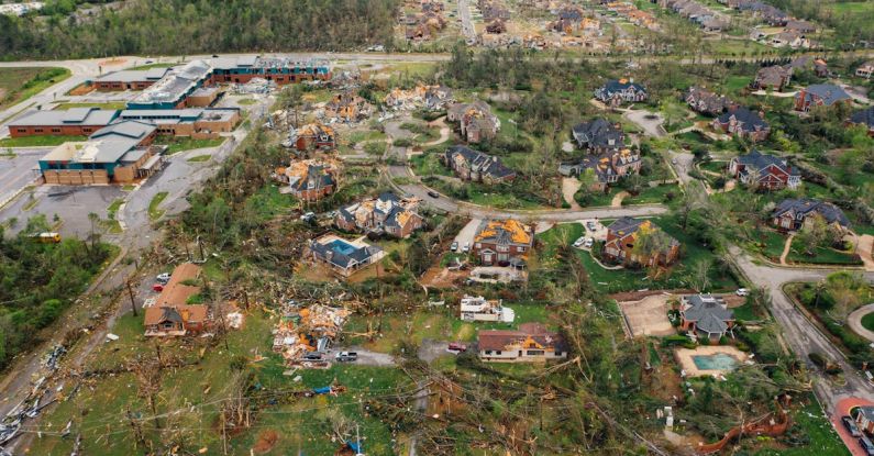 Outcomes - Aerial view of tornado impact on small settlement cottages with destroyed roofs windthrown trees and bent electricity transmission lines