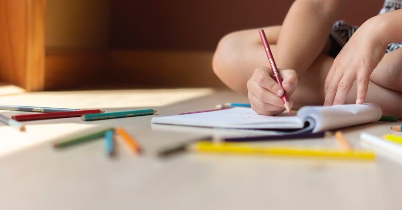 Cross-Functional Skills - Crop kid sitting on floor and writing in notebook